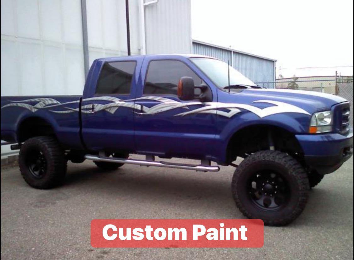 A lifted blue pickup truck with custom white and gray flame paint job on the hood and sides. The text 'Custom Paint' appears at the bottom of the image.