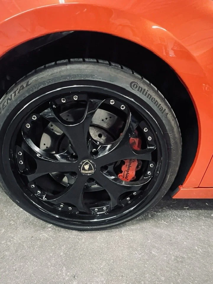 Close-up of a black alloy wheel on a red sports car, with a Continental tire and visible red brake caliper.