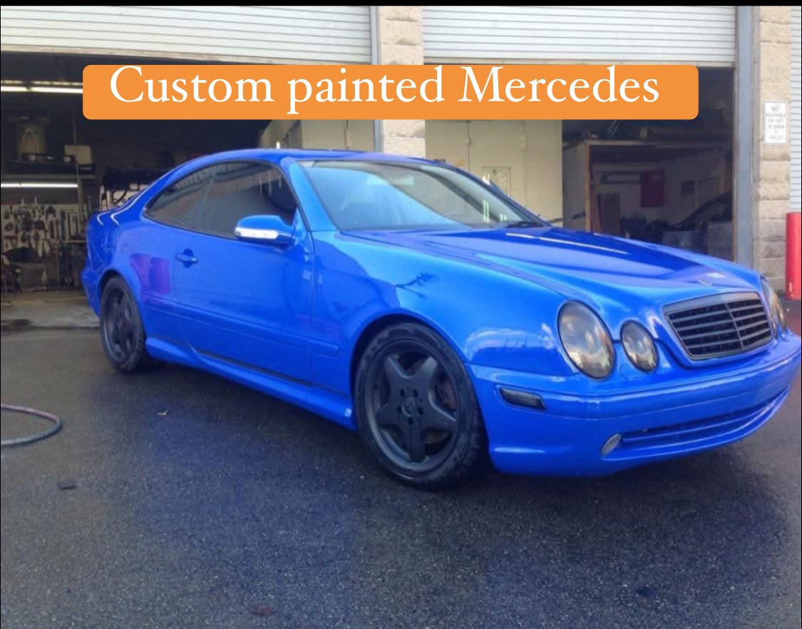 A blue Mercedes car with custom painted body parked outside a garage.