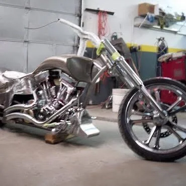 Custom chopper-style motorcycle in a garage, with chrome accents and a minimalist design.