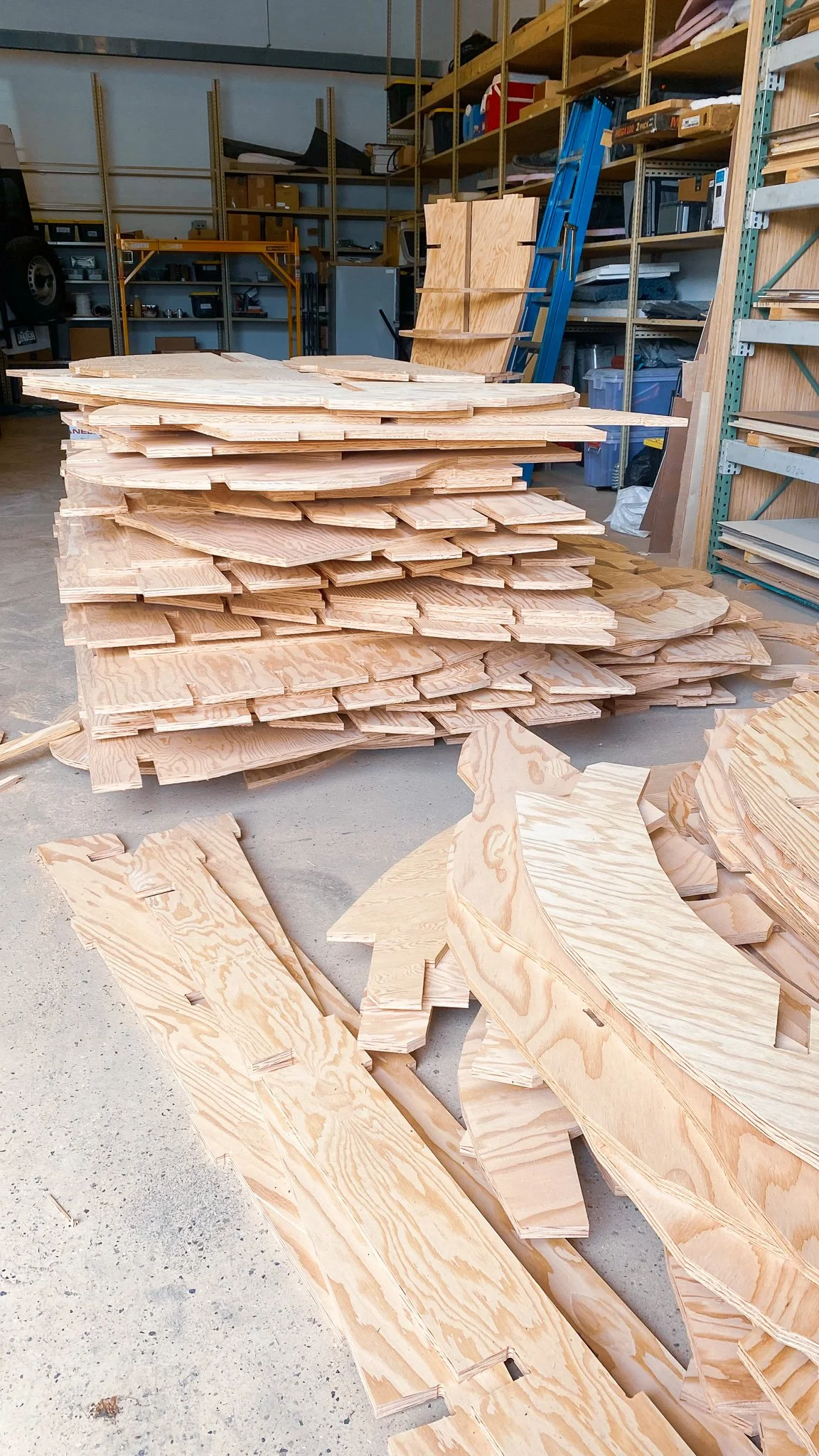wooden pieces stacked on the floor in a woodworking workshop.