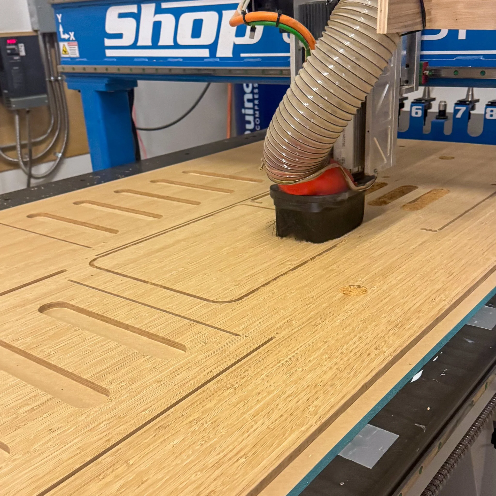 A CNC woodworking machine carving out slots into a wooden board.