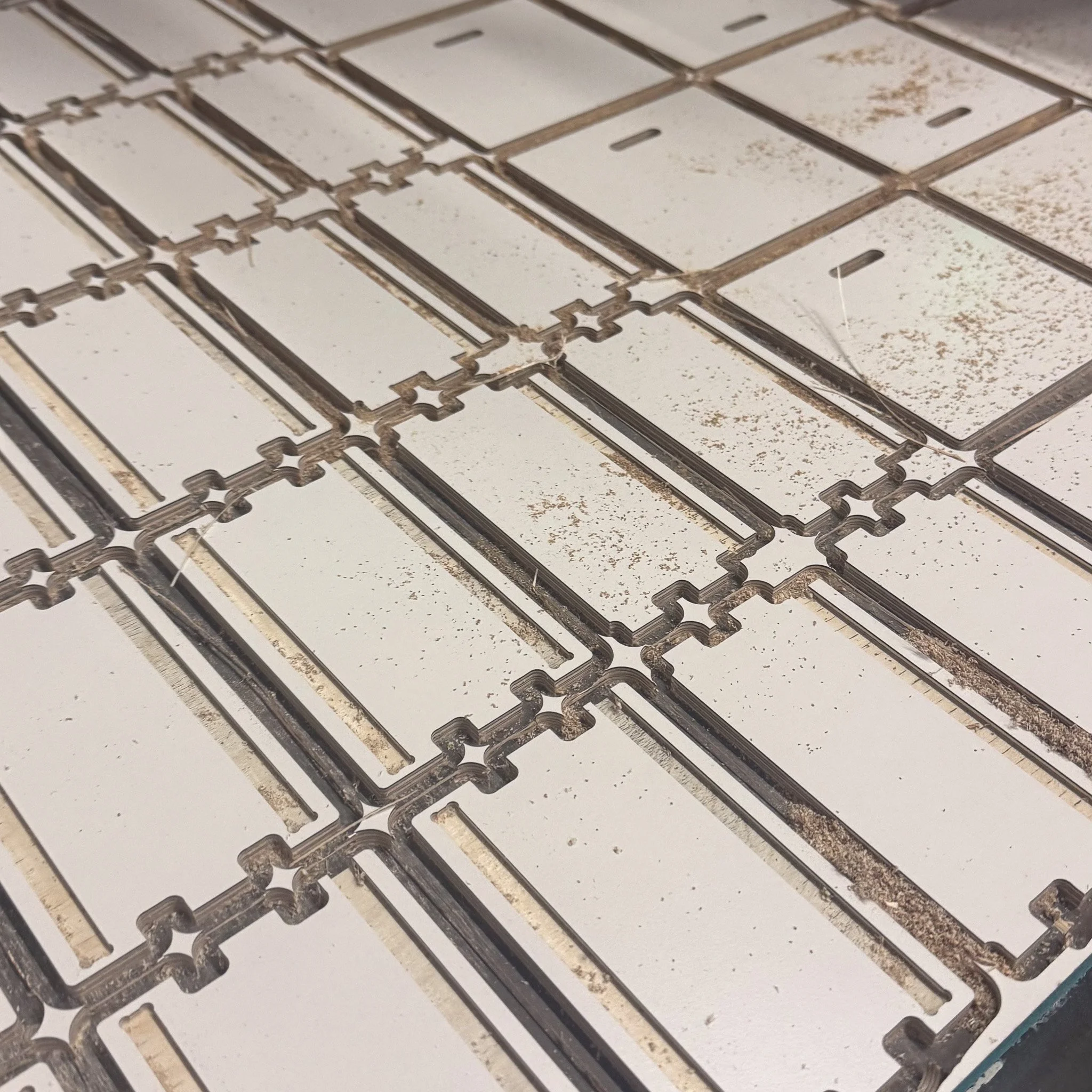 Close-up of a metal tile cutter with rectangular cutouts, some with visible rust and dust.