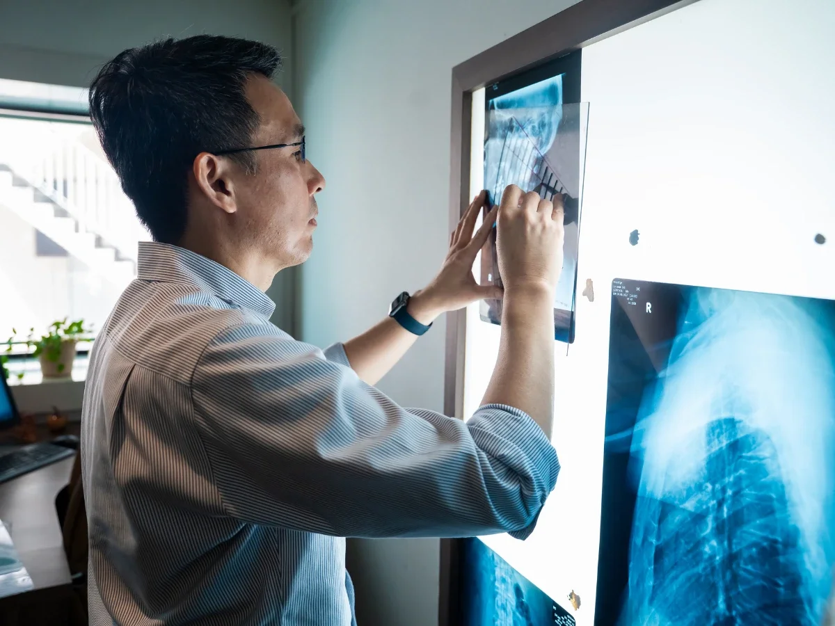 Chiropractor reviewing patient’s X-ray images during assessment in clinic