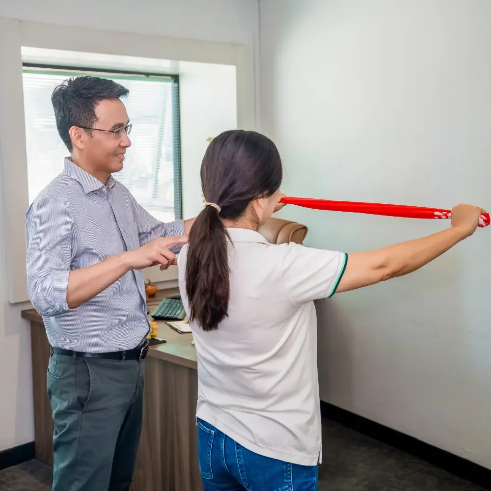Chiropractor guiding patient through shoulder mobility exercise using resistance band