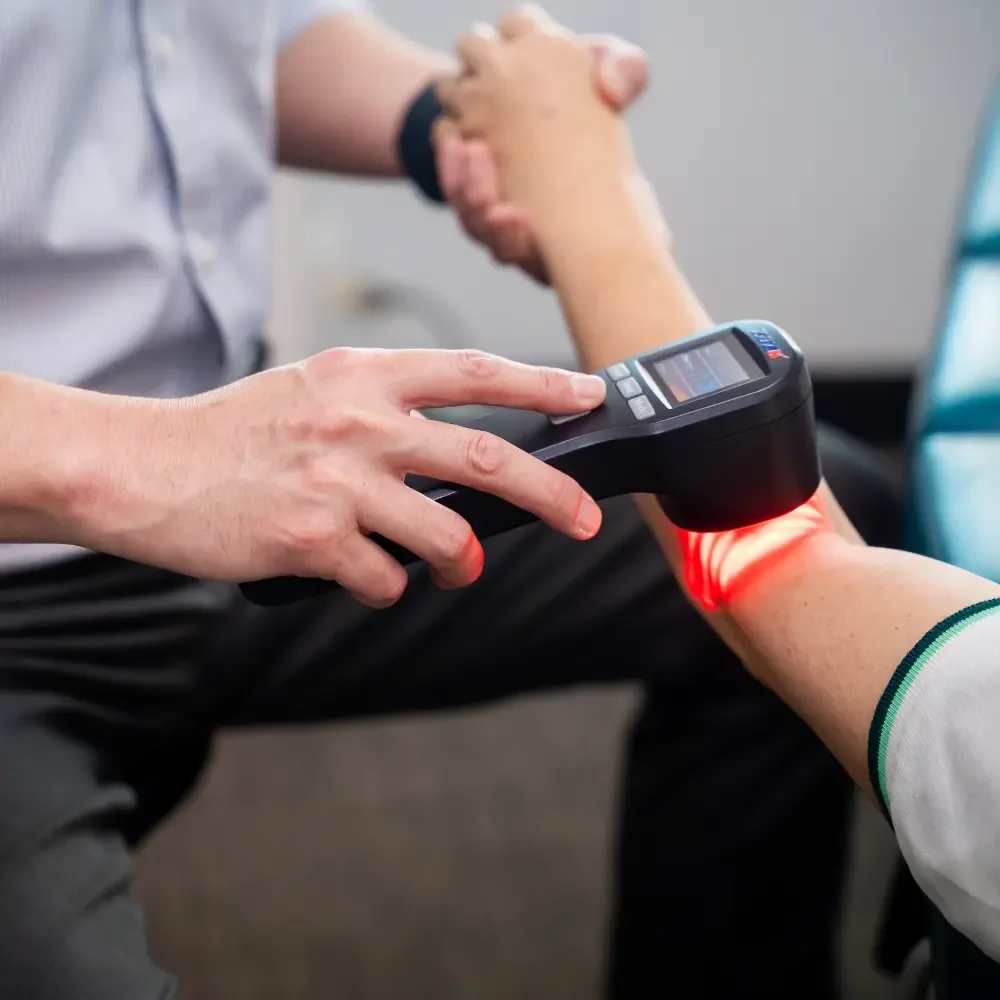 Chiropractor using shock wave therapy device on patient’s arm during treatment