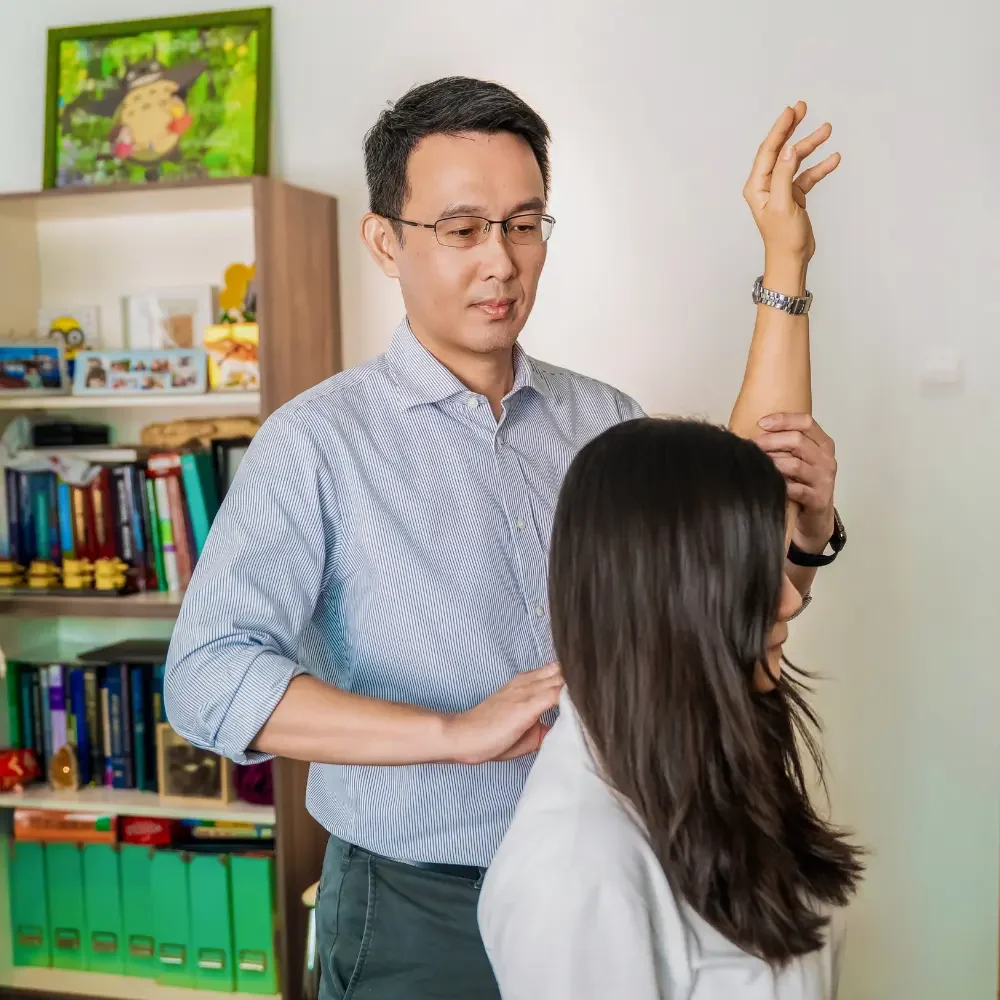 Chiropractor assessing patient’s shoulder movement and mobility in clinic