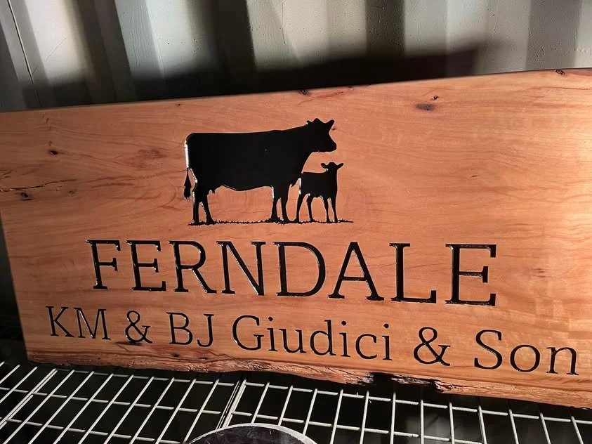 Wooden family name sign with cow and calf silhouette, reading 'FERNDALE KM & BJ Giudici & Son'.