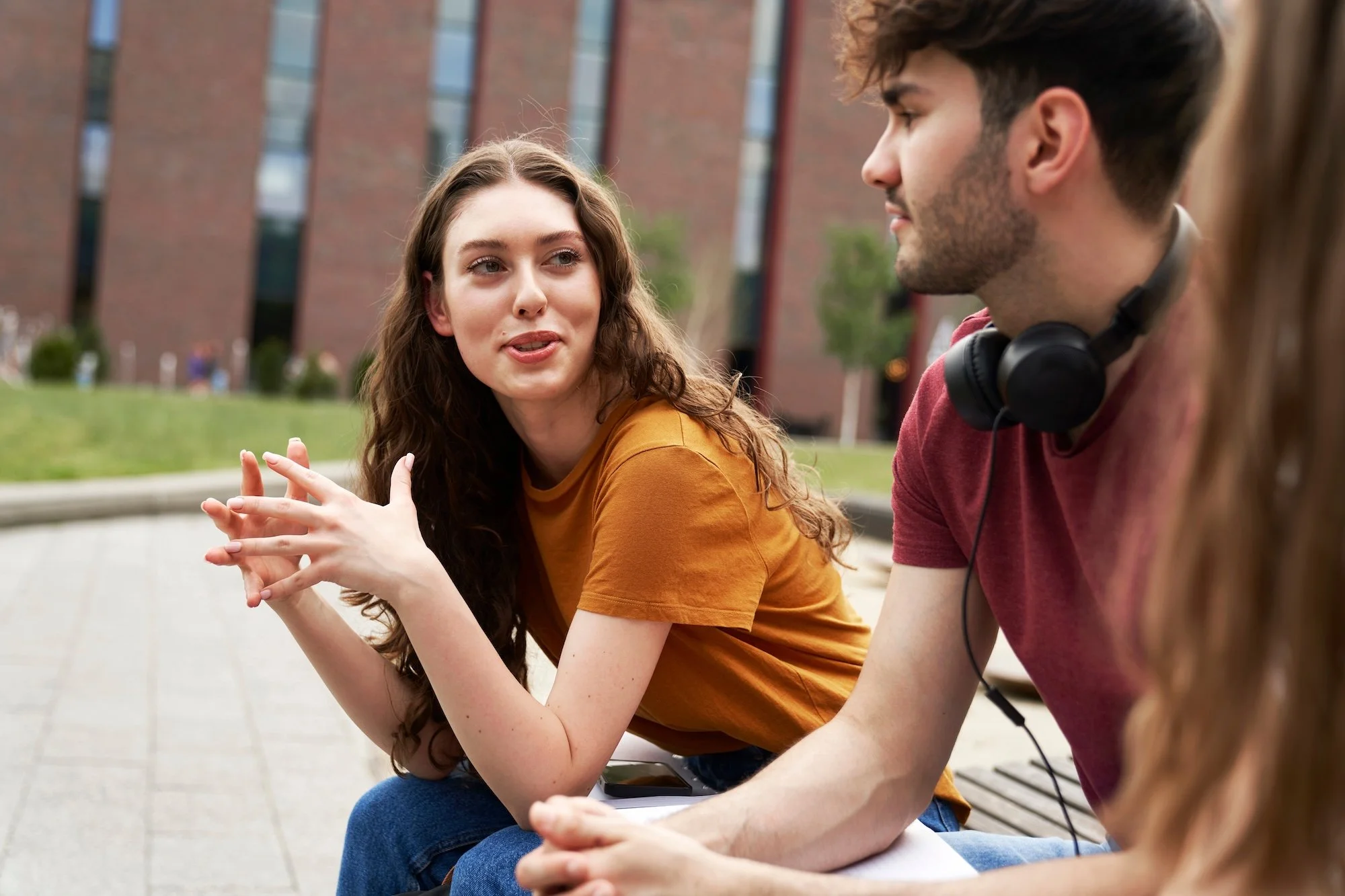 Two students engaged in conversation sitting in the outdoors