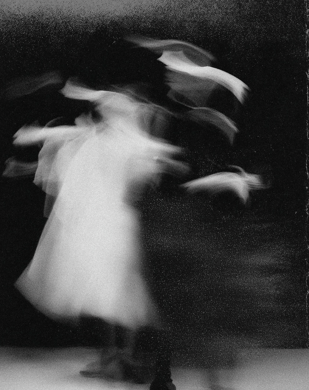 Black and white abstract photograph of a woman in a dress, captured with motion blur.
