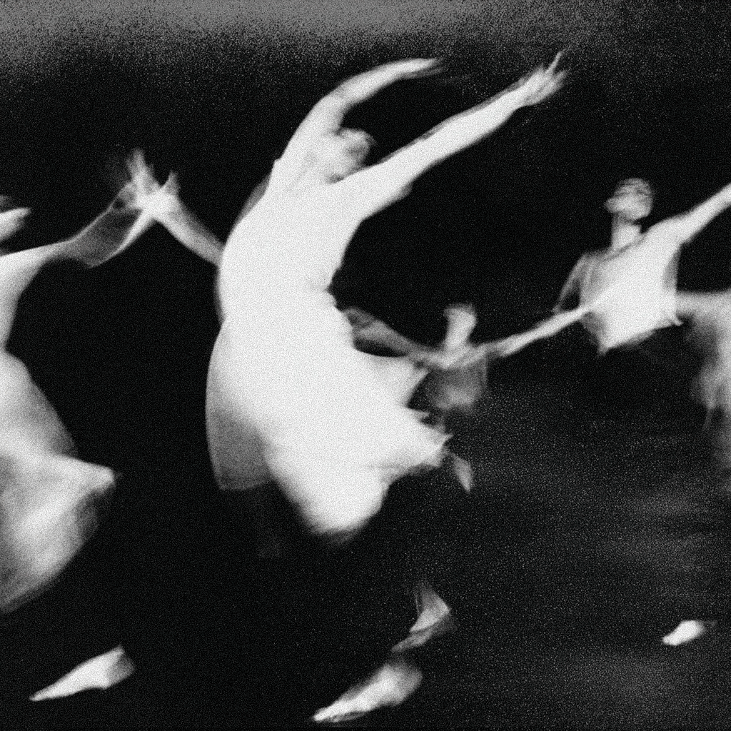 Several ballet dancers in white costumes practicing or performing on a dark stage.