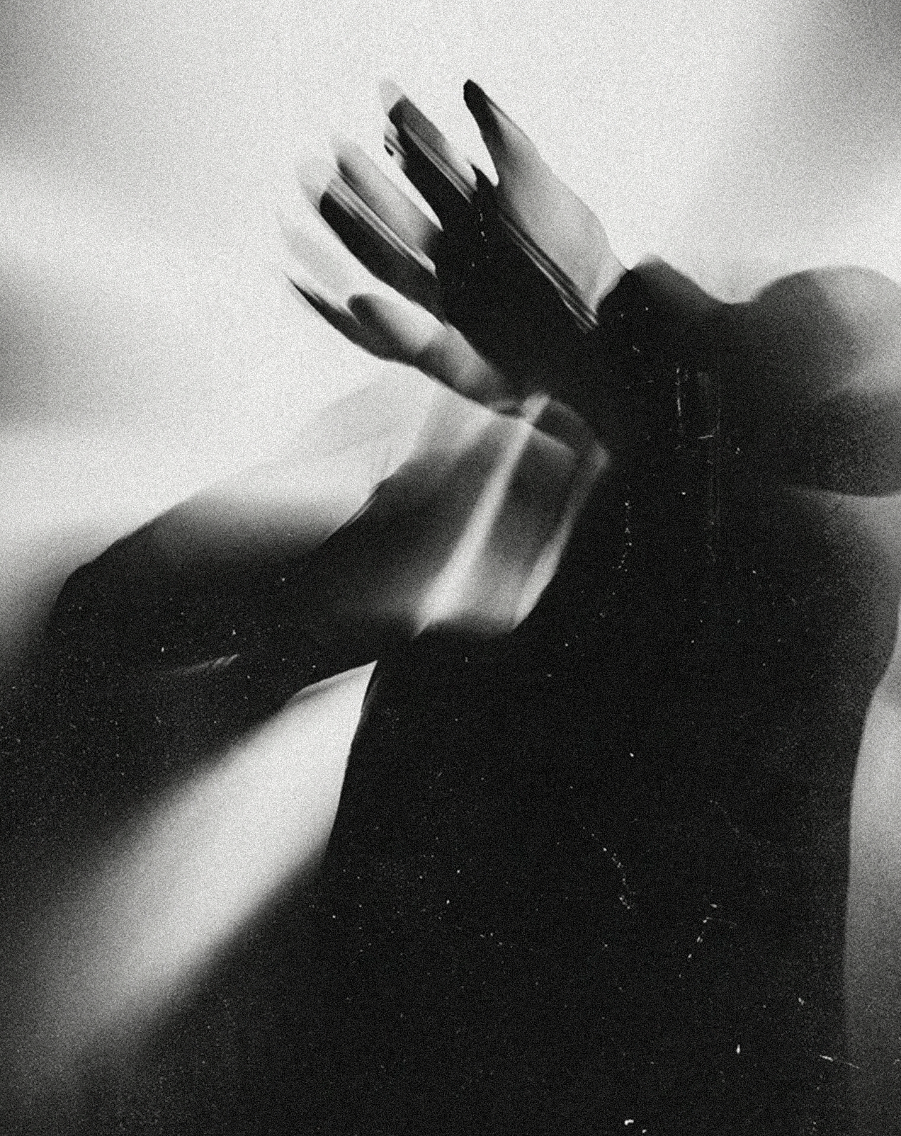 Close-up black-and-white photo of two hands with long nails, touching each other, with one hand covered by a black sleeve.