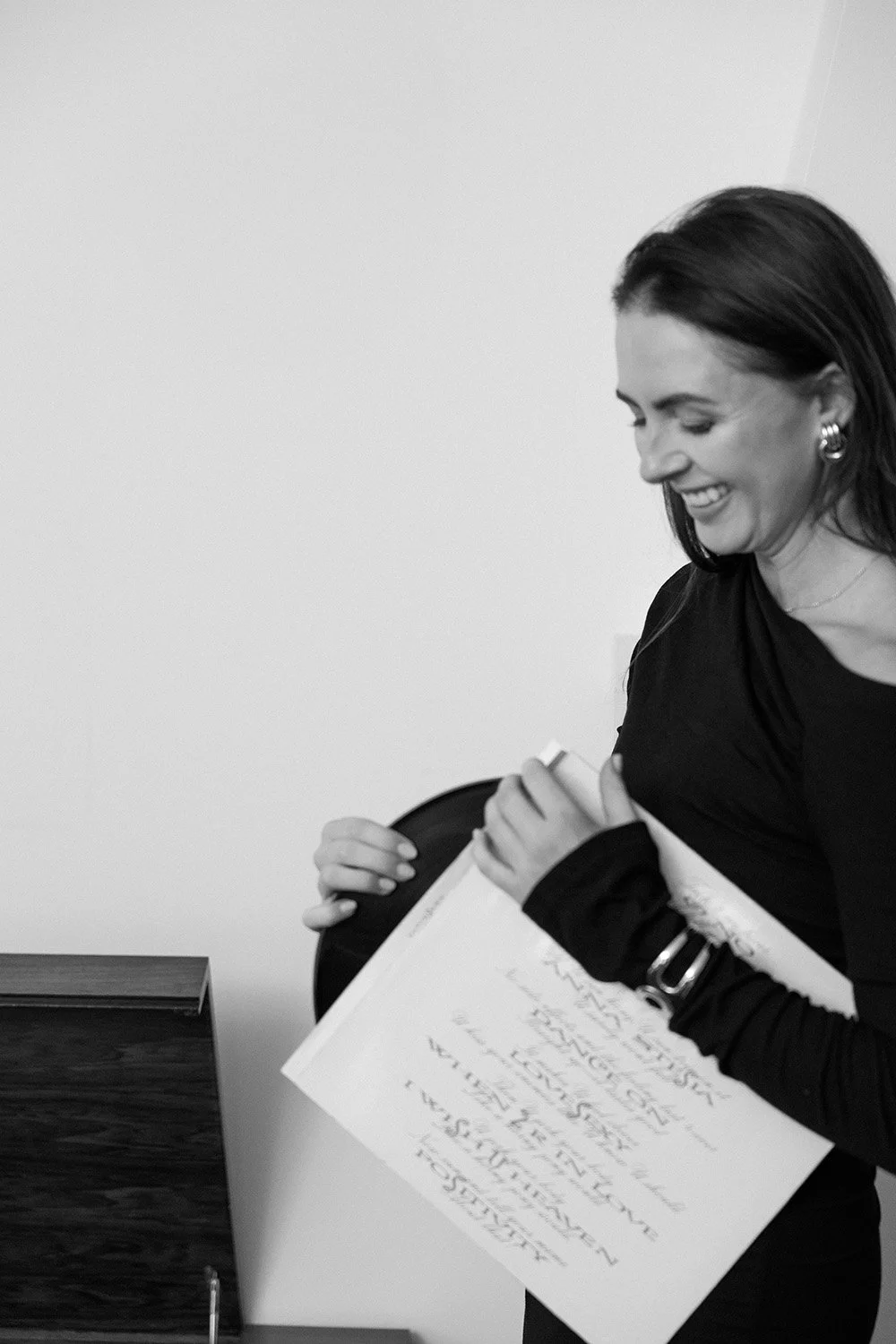 A woman smiling and holding a document in an office setting.