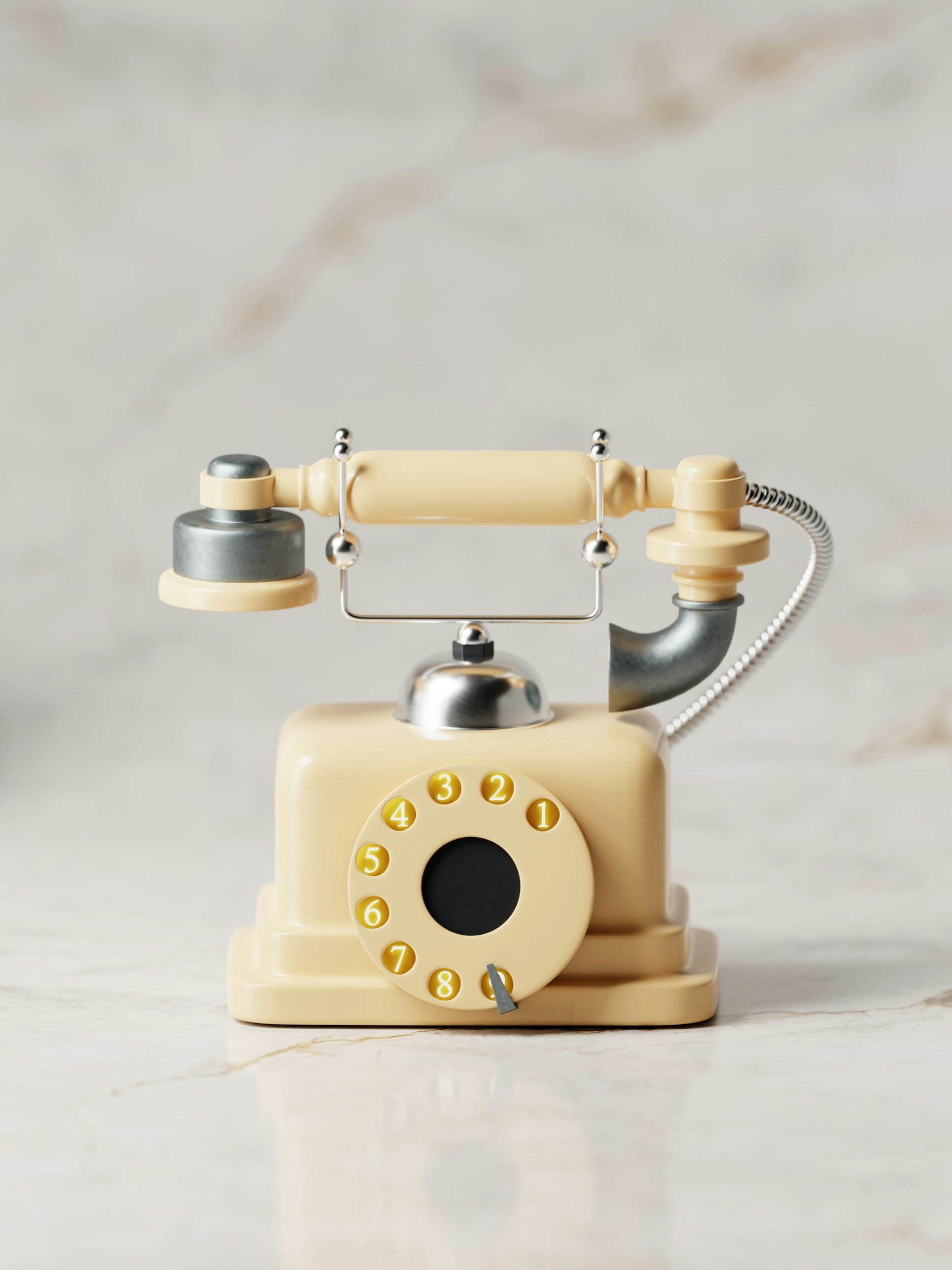 Vintage beige rotary telephone with a black dial and yellow numbered buttons on a marble surface against a plain background.