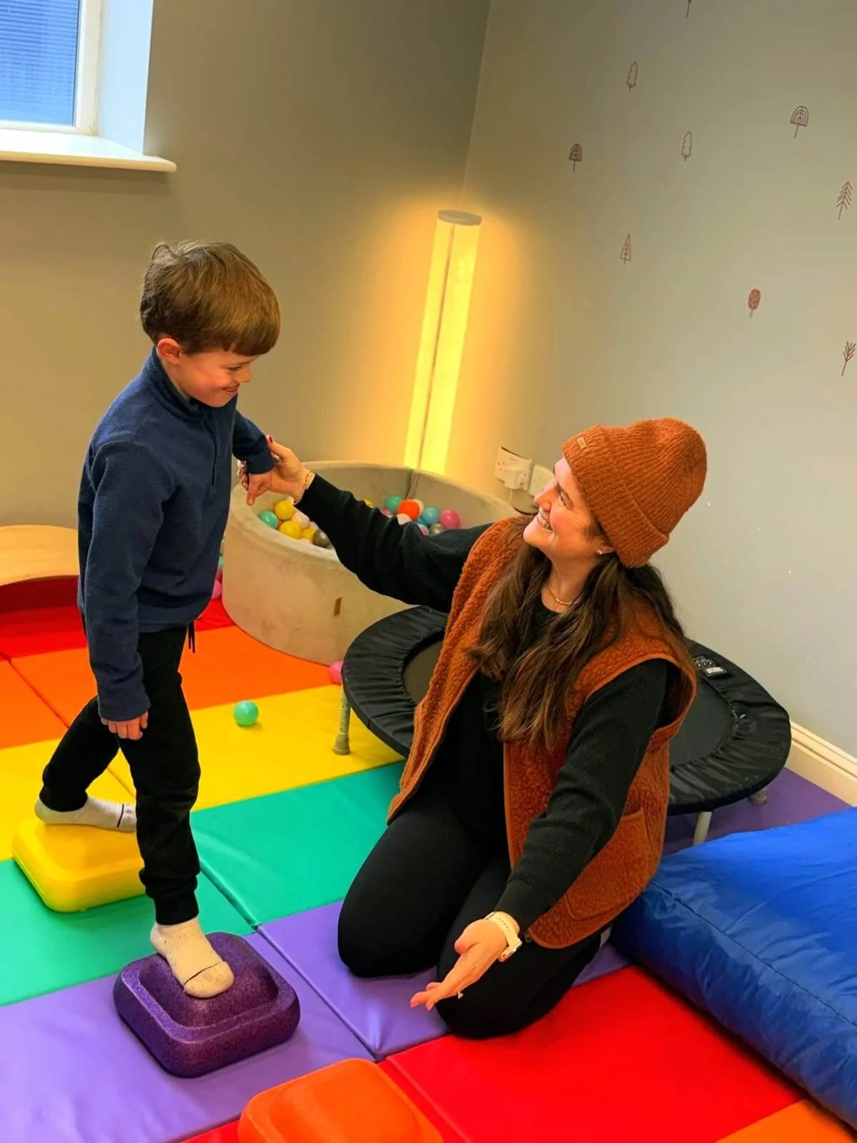 Rachel Maunsell delivering Occupational Therapy to her client on a brightly-coloured floor mat