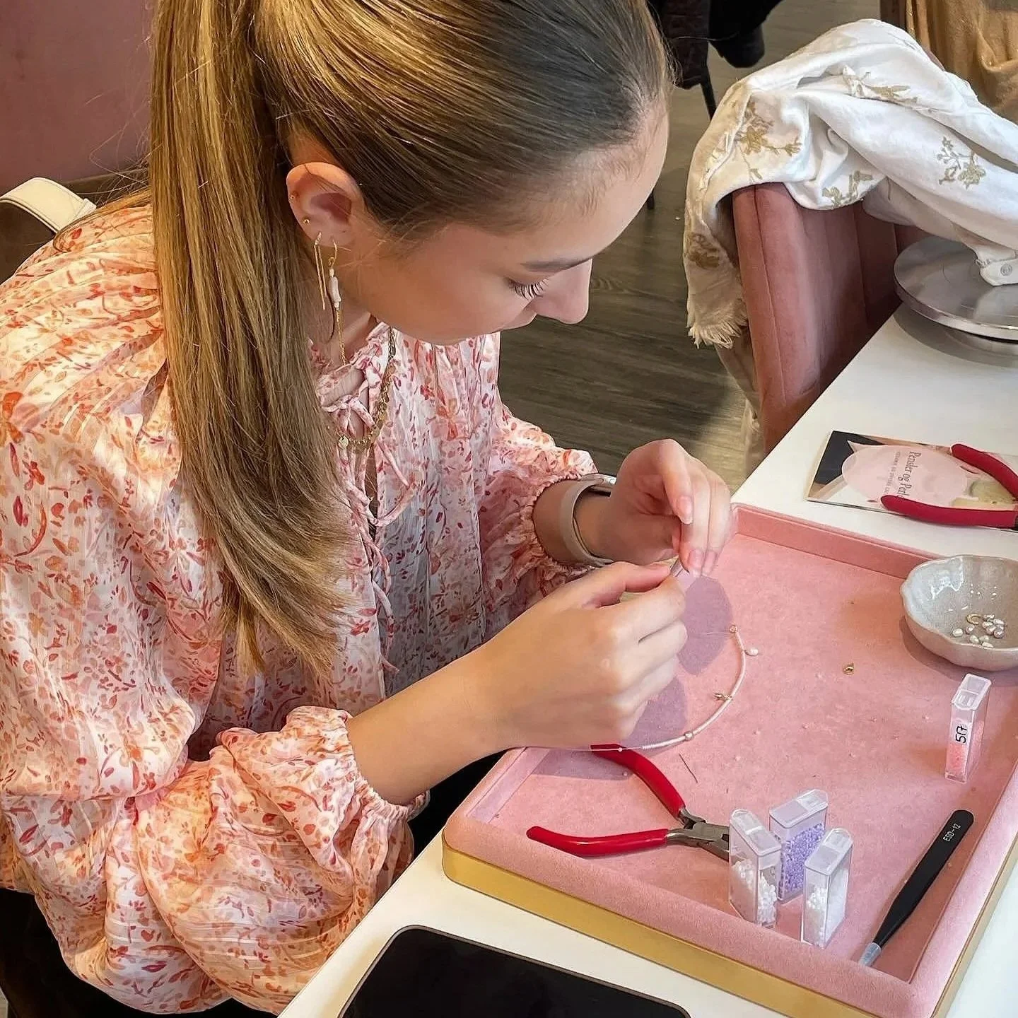 Kvinde laver smykke i et værksted med smykkeværktøj og materialer