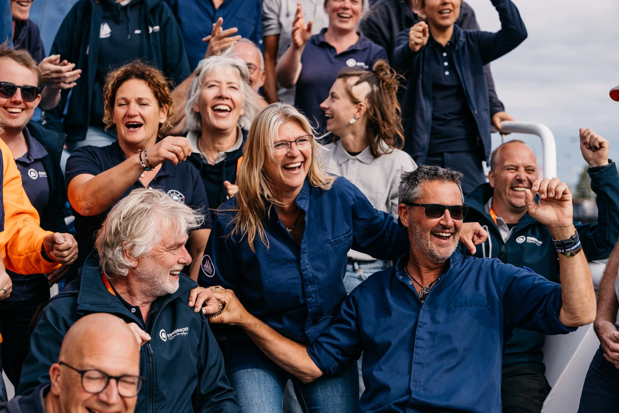 Group of people outdoors, smiling, and celebrating together.