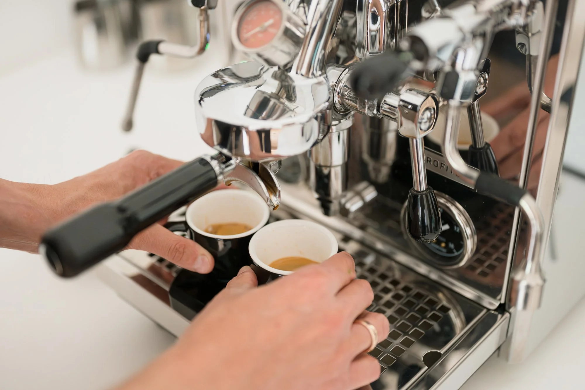 Perfekt extrahierter Espresso auf einer digitalen Kaffeewaage neben ACME Tassen und einer Profitec Siebträgermaschine im Home-Barista-Setup.