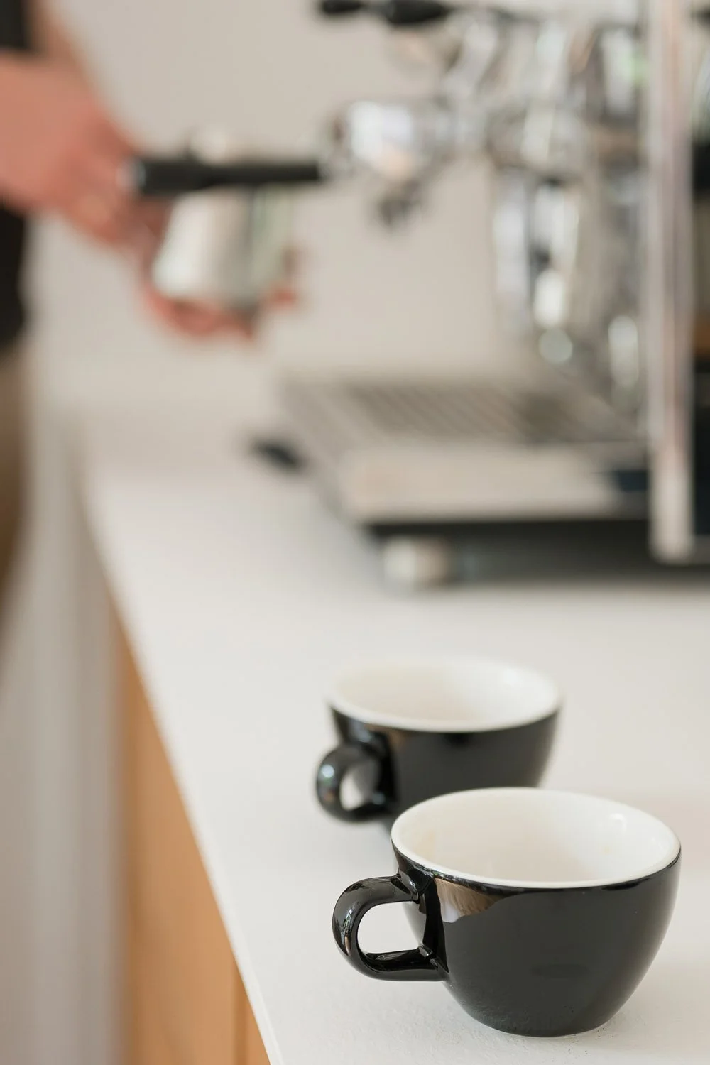 Zwei Espressotassen im Rahmen eines Home-Barista Coachings für Paare, während im Hintergrund Kaffee zubereitet wird.