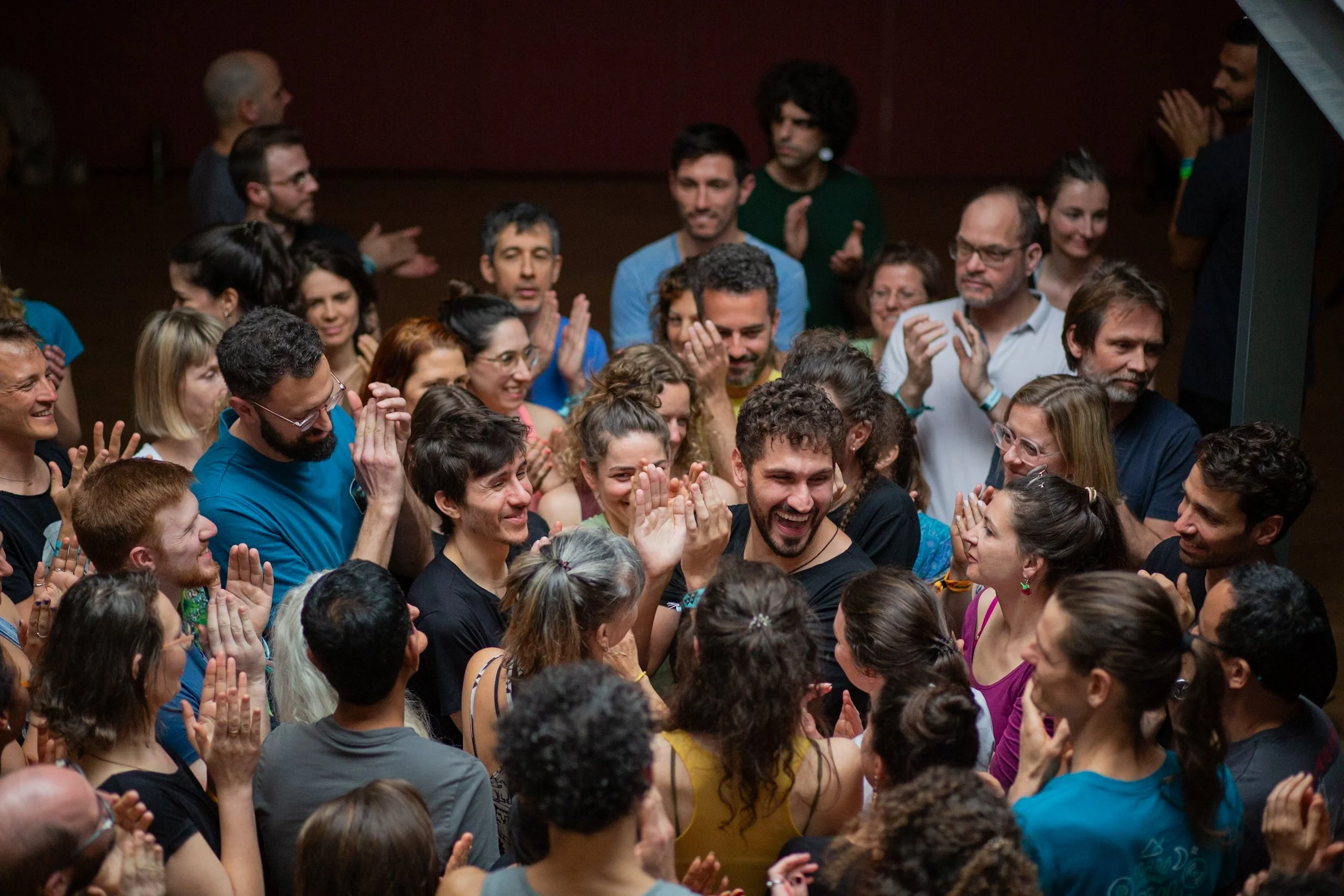 Group of people at a celebration or party, smiling, clapping, and engaging with each other in a lively atmosphere.