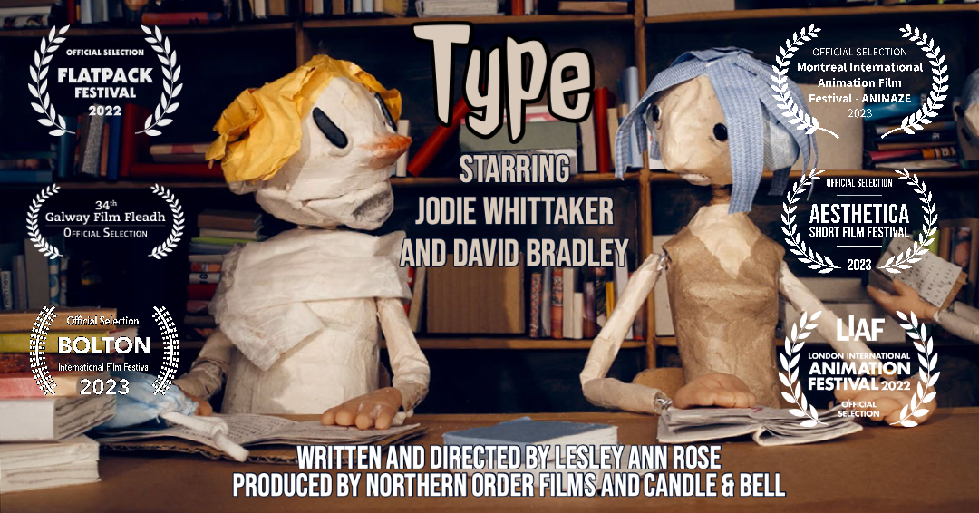 Two paper-mâché puppets sitting at a desk with books, with awards and festival selections around them, promoting the film "Type" starring Jodie Whittaker and David Bradley.