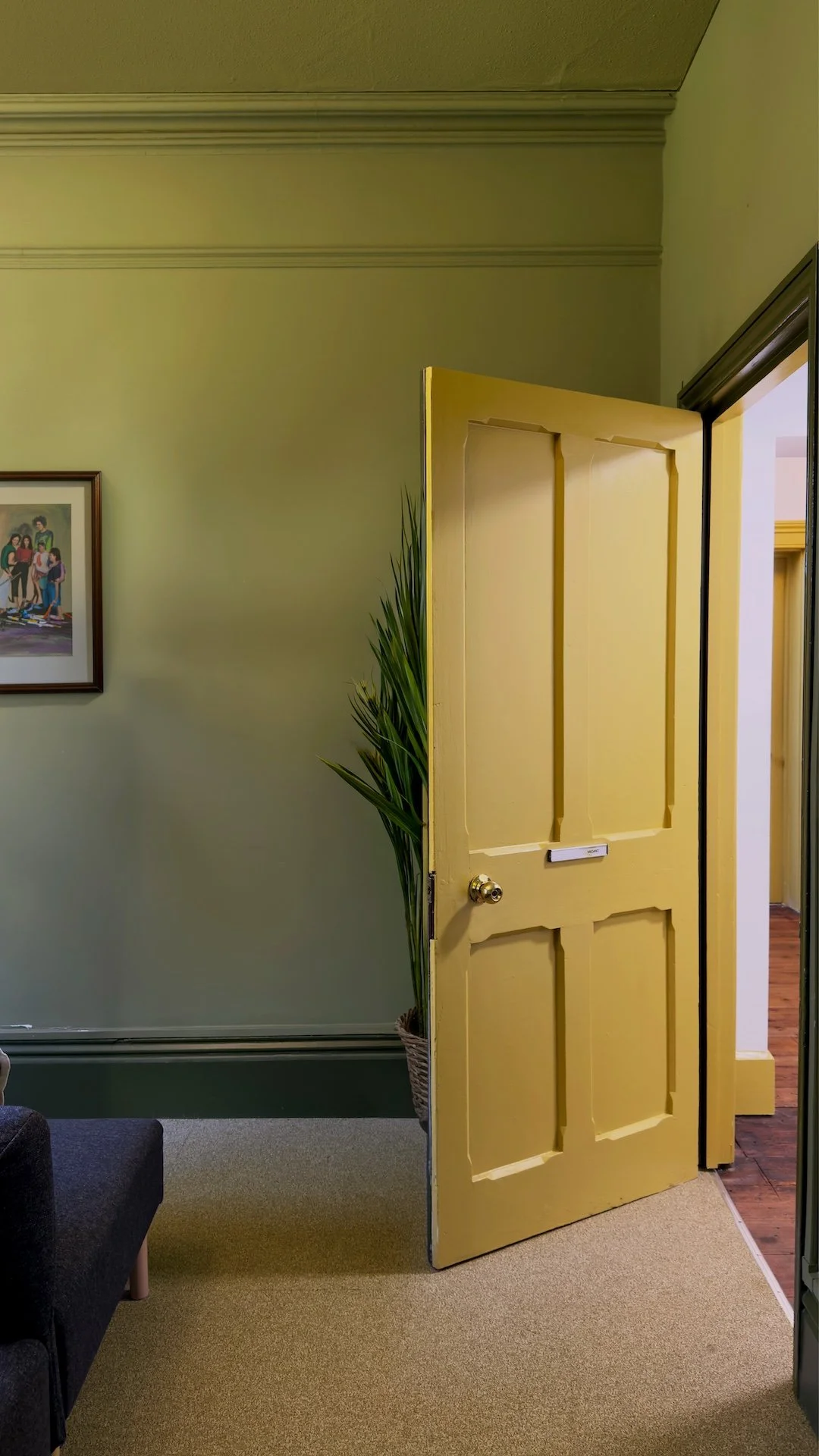 Heritage interior featuring olive green walls, warm yellow doors and restored architectural detailing by Studio EWW 