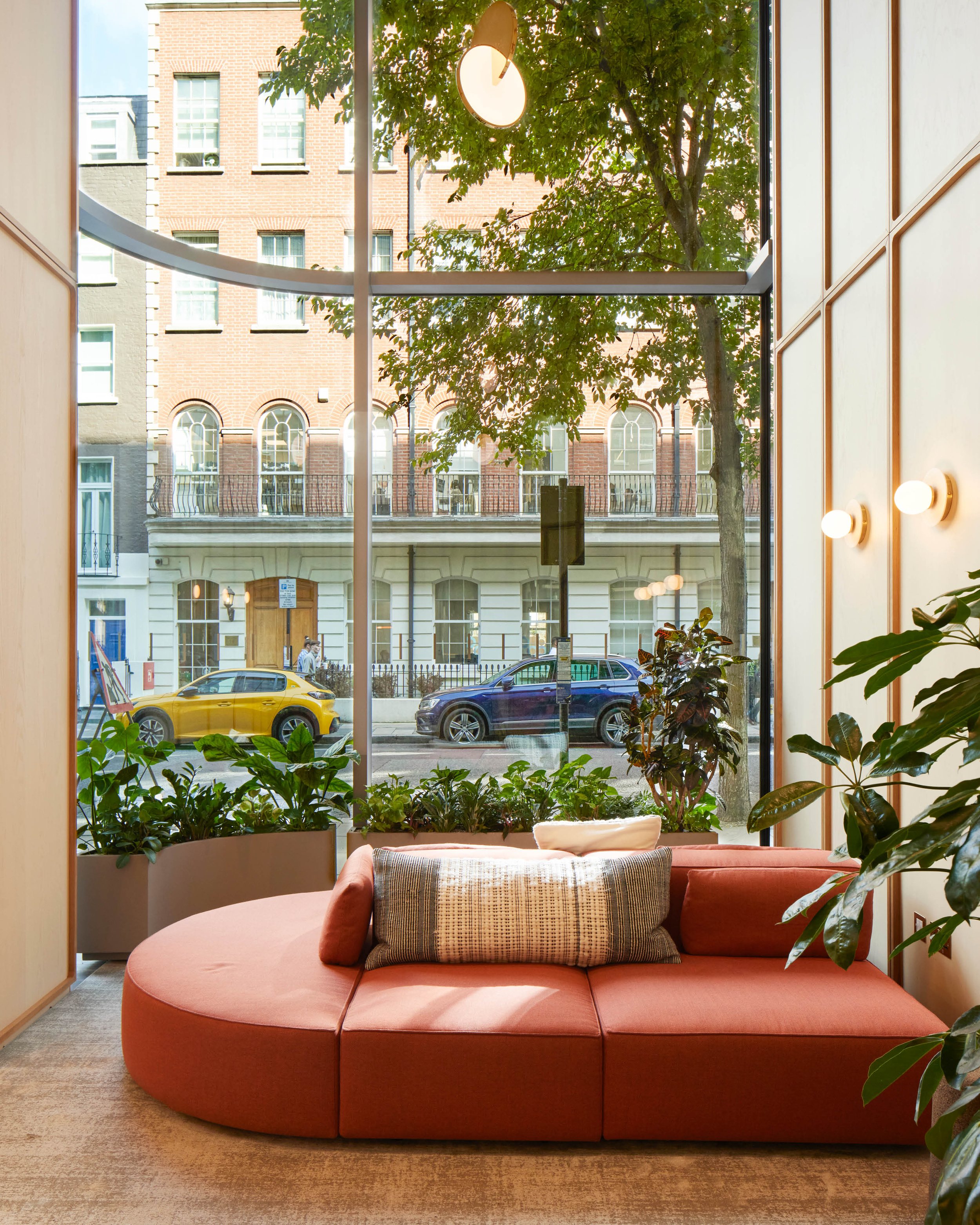 Contemporary hospitality interior by Studio EWW featuring curved seating, biophilic planting and floor-to-ceiling windows with natural light-filled workspace design