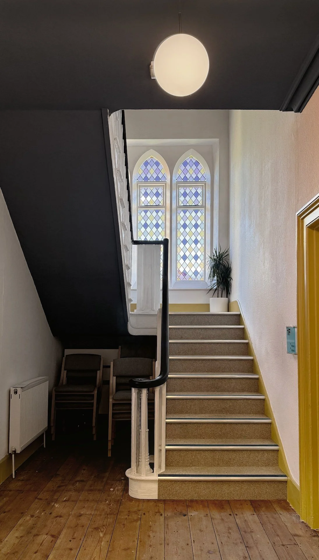  Restored staircase interior with stained glass windows and contemporary globe lighting by Studio EWW 