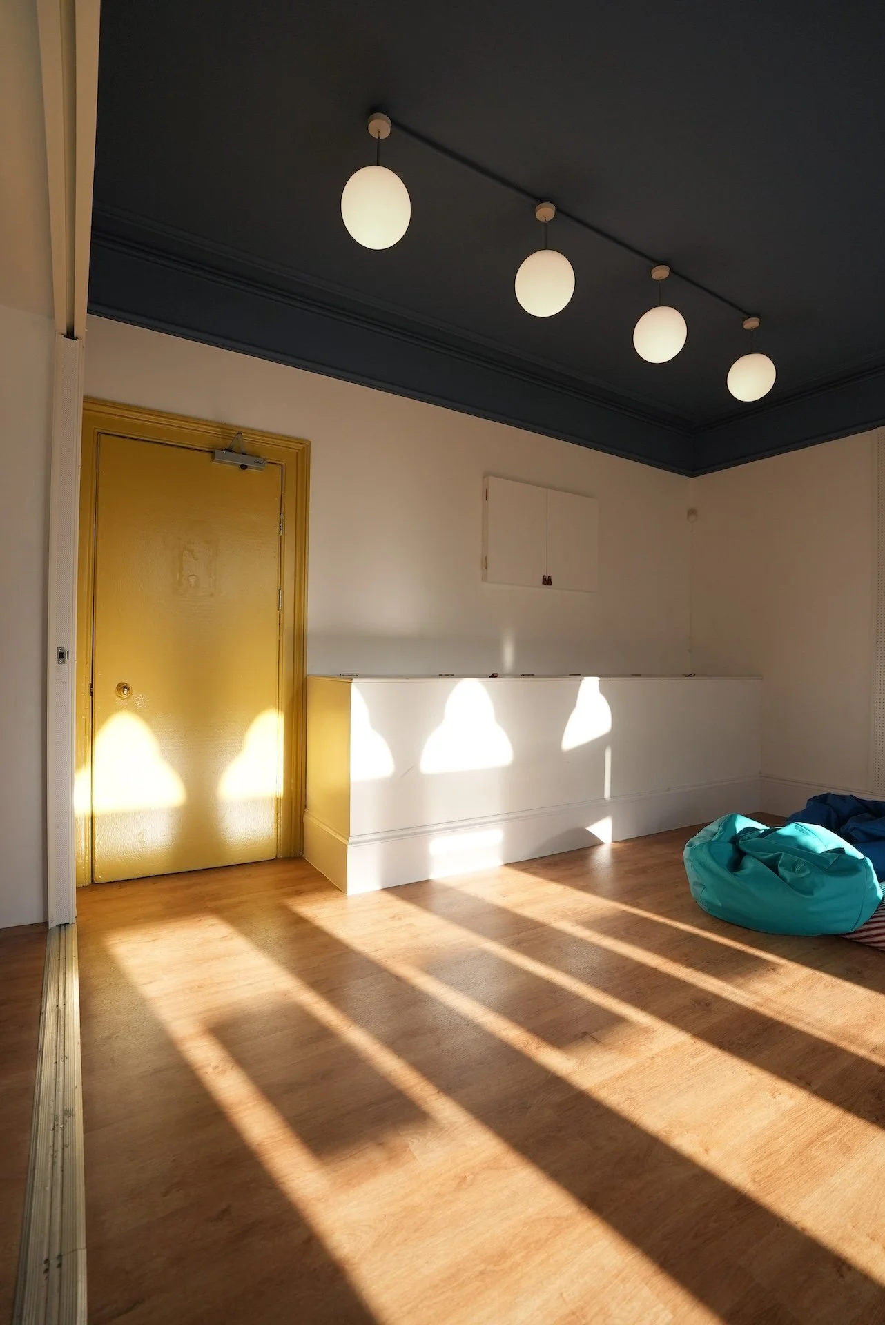  Minimal communal room with pendant lighting and dramatic sunlight shadows by Studio EWW 