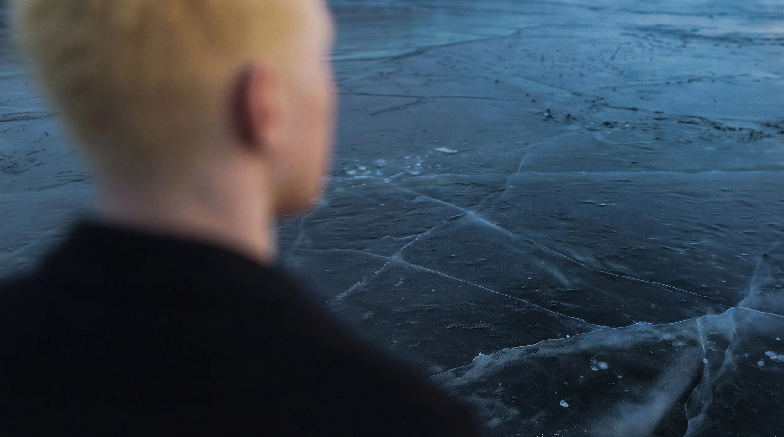 "Over-the-shoulder view looking out across a desolate glacial sheet with low-hanging surface mist. Atmospheric mood shot from the Arctic Void campaign."