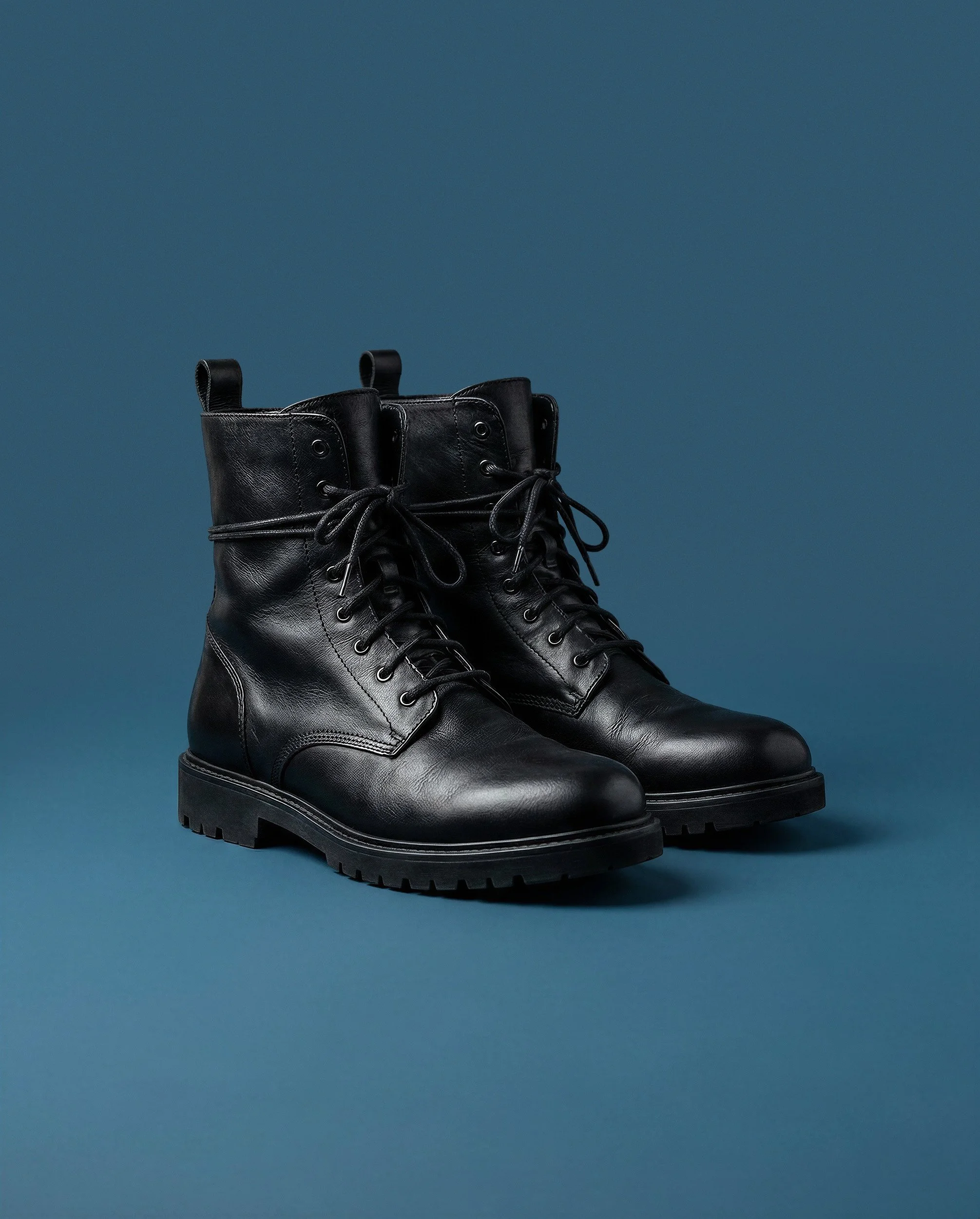 "Commercial product shot of black leather boots in a studio setting. Zero-logistics high-fashion footwear photography created with generative AI technology."
