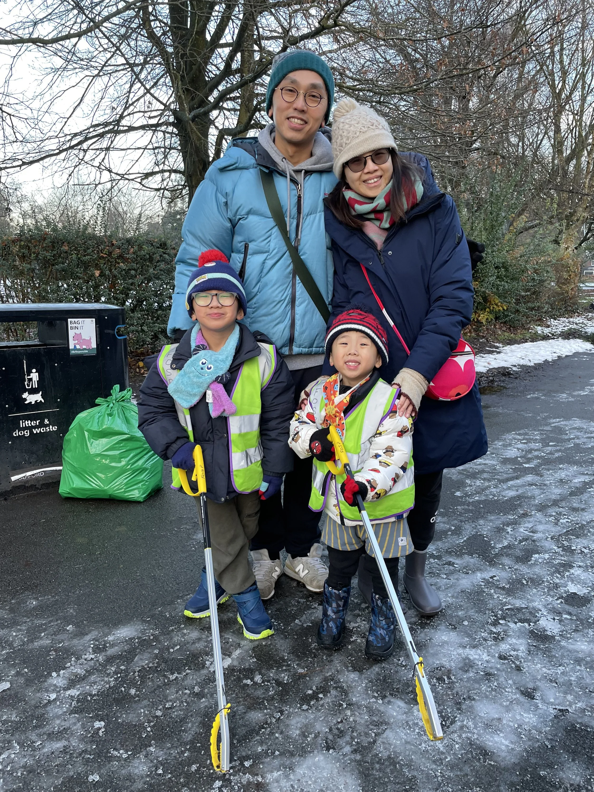 a local family helping to collect rubbish from the park, on an icy morning in the park