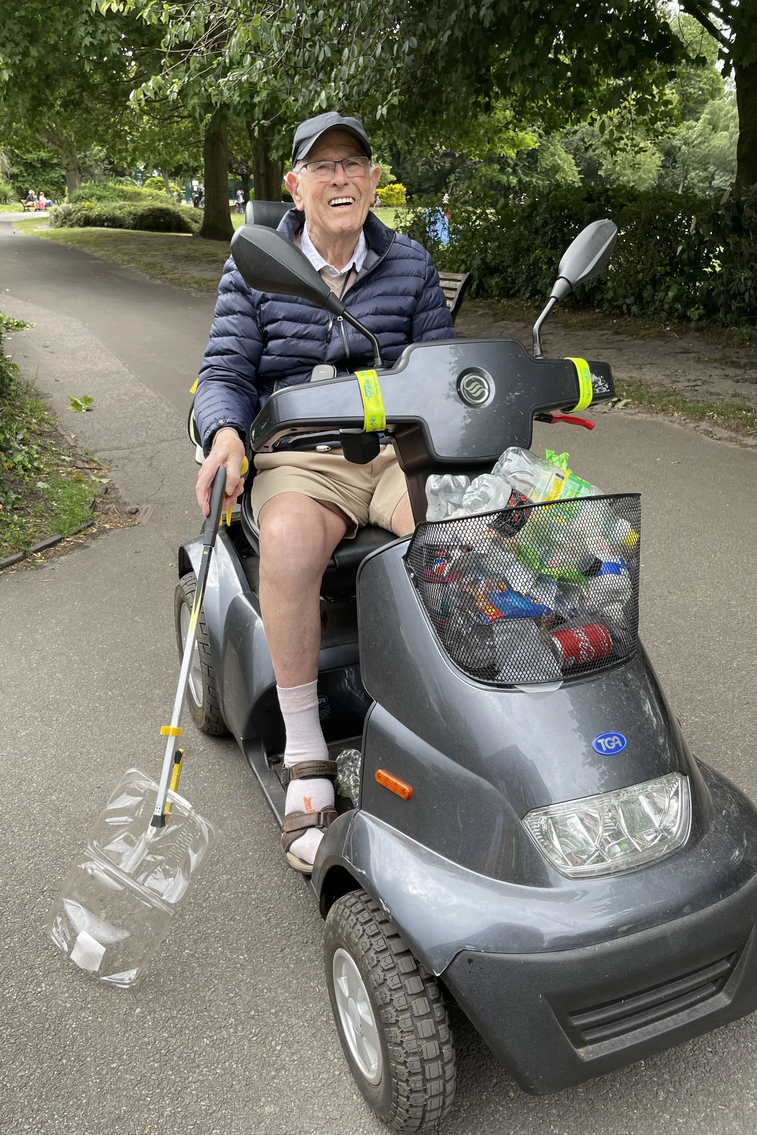 an elderly gentleman on a mobility scooter helping to collect rubbish in the park