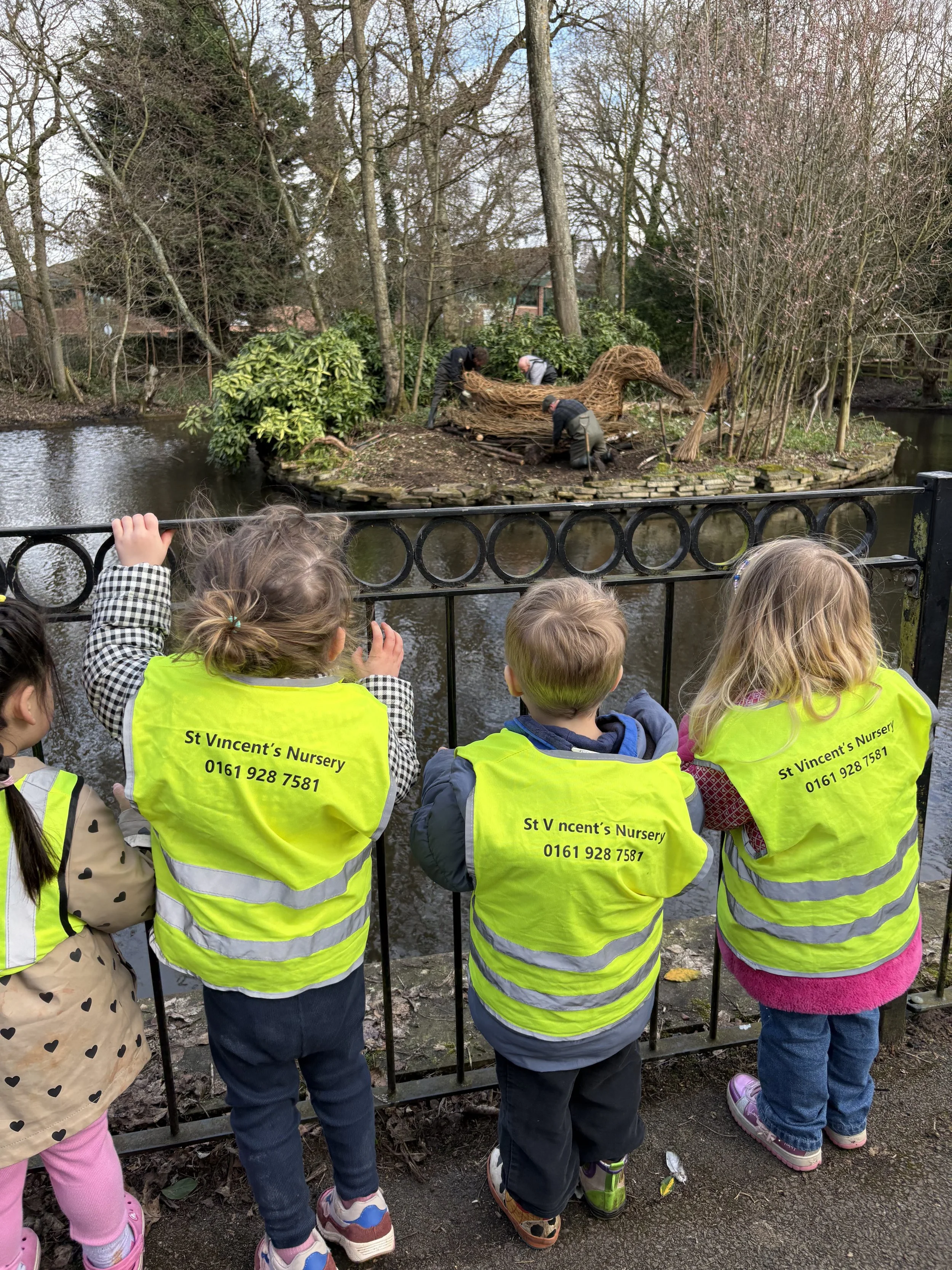 Vinny the 10ft duck made from willow branches, in his new home at stamford park as children from St Vincents Nursery look on