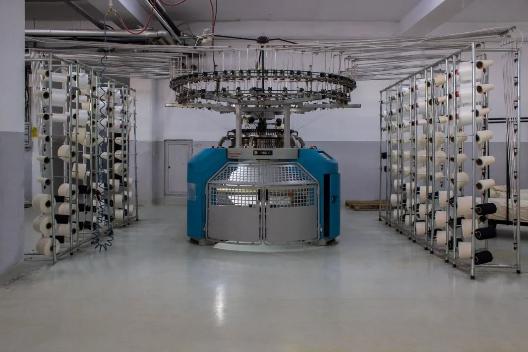 How your T shirt fabric actually gets made 👀

This is a circular knitting machine, one of the most commonly used machines for jersey fabric production.

Hundreds of yarn cones feed simultaneously into the machine while needles continuously loop the 
