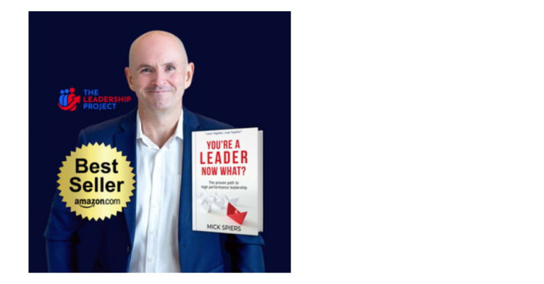 A man in a dark suit standing against a dark background. He is holding a book titled 'You're a Leader Now What?'. There is a 'Best Seller' badge and a logo for 'The Leadership Project' on the image.