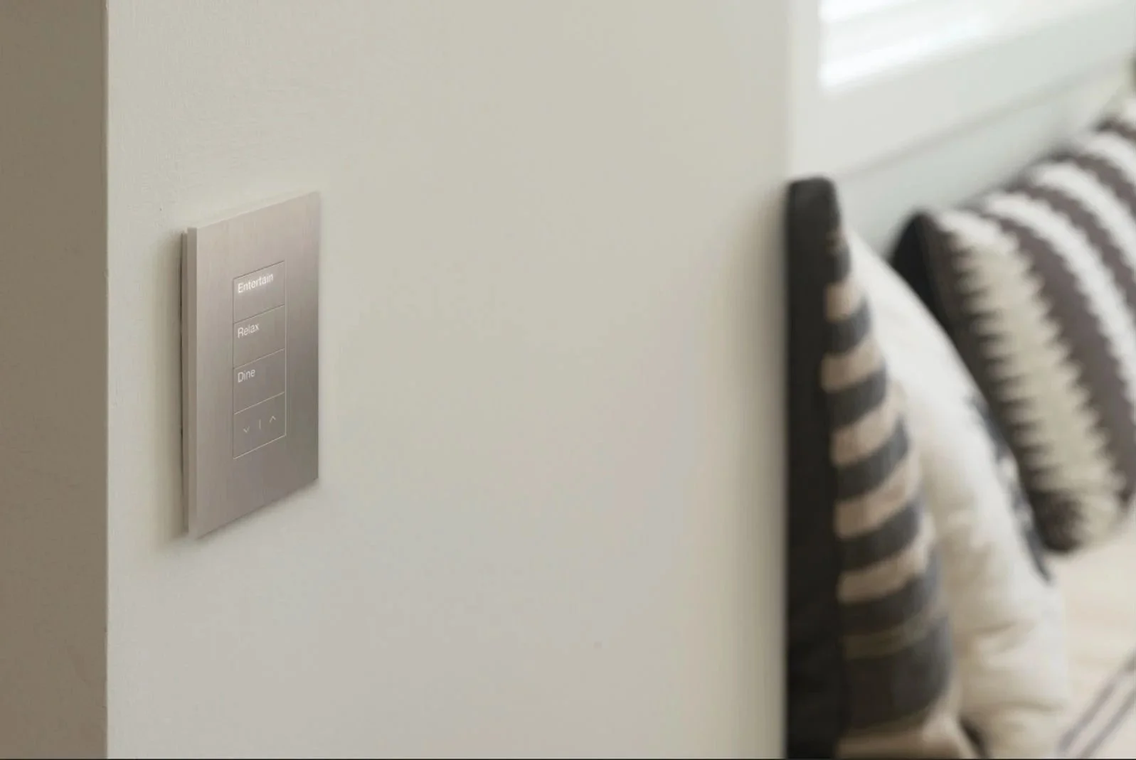 A wall-mounted Lutron lighting control panel in a well appointed master bedroom.