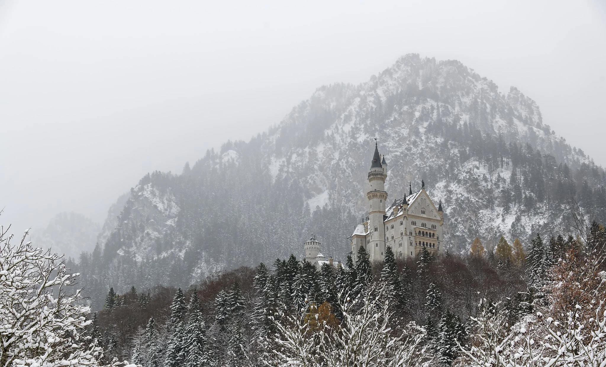 Snow-covered castle on a hill with a mountain in the background. Germany.