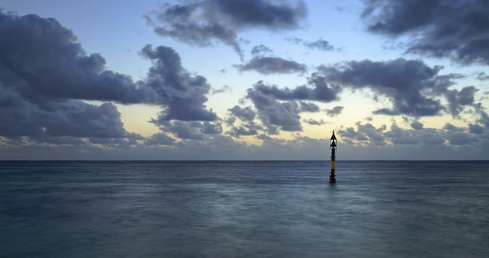 Ocean with a solitary navigational marker or buoy and a cloudy sky at dusk or dawn. Jurien Bay Western Australia.
