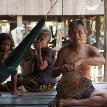 A Laotian family sits in the shade of their home, in a village in Ratanakiri, northwester Cambodia