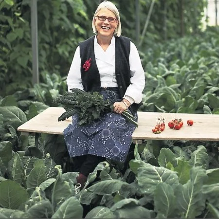 Irish chef and food champion, Darina Allen, sits on a bench in a field of kale