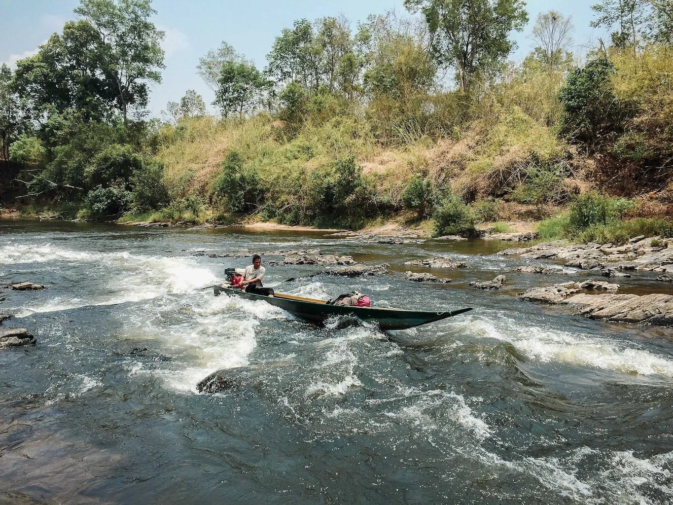 A motor boat bumping over rapids on the Sesan River in Ratanakiri Province, Cambodia