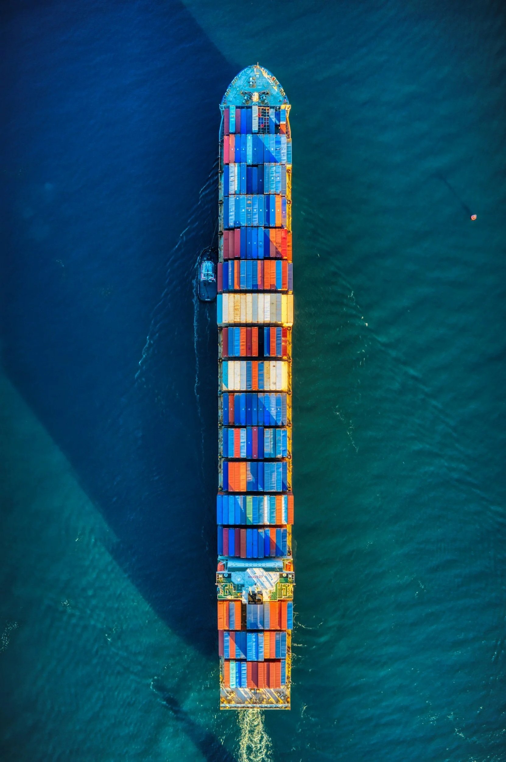Aerial view of a cargo ship loaded with colorful shipping containers sailing on the ocean.