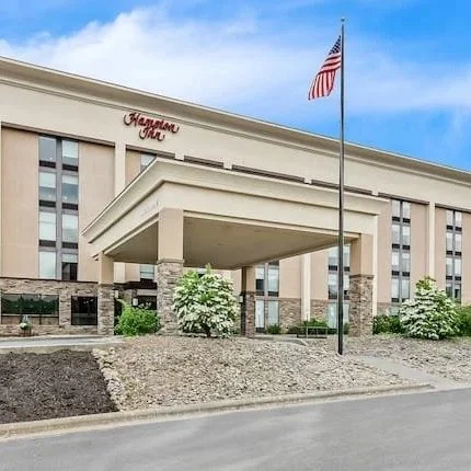 The exterior of a Marriott hotel with an American flag flying on a flagpole in front.