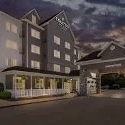 A modern luxury hotel building at night with a well-lit entrance and a covered driveway.