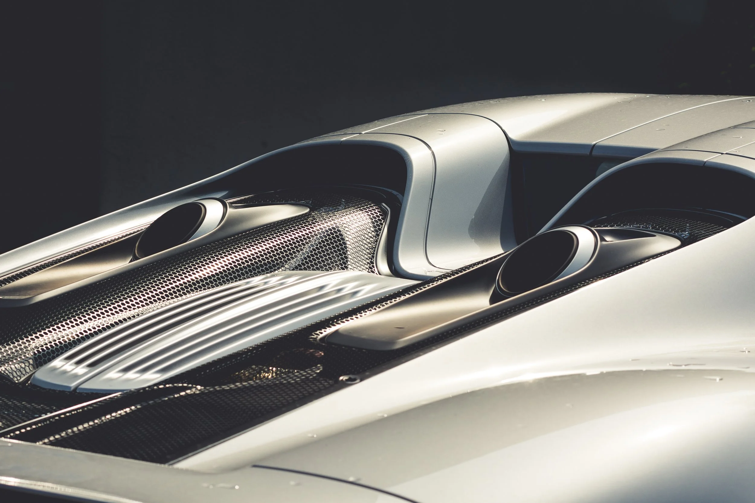 Close-up of the front section of a silver sports car, highlighting its aerodynamic design and vents.