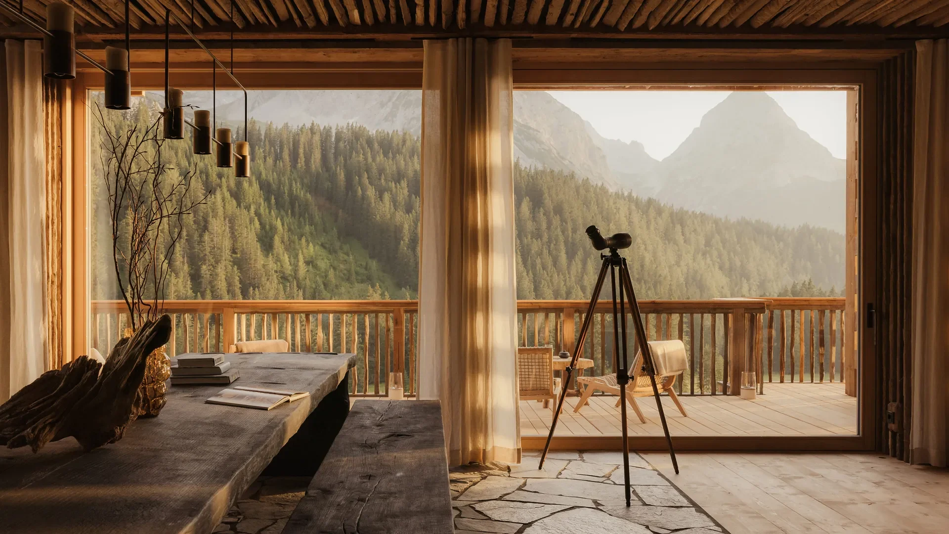 A cozy cabin interior with a large window showing a mountainous forest landscape, a telescope near the window, and a rustic table with books and decorative objects inside.
