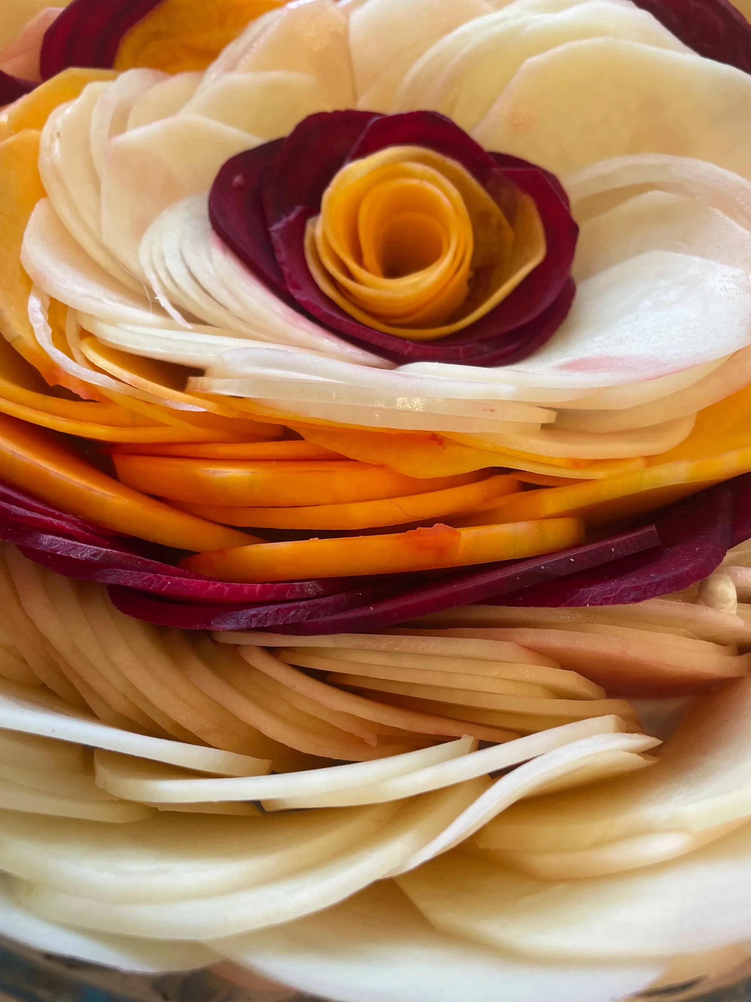 Colored layers of vegetable slices arranged in a rosette pattern resembling a flower.