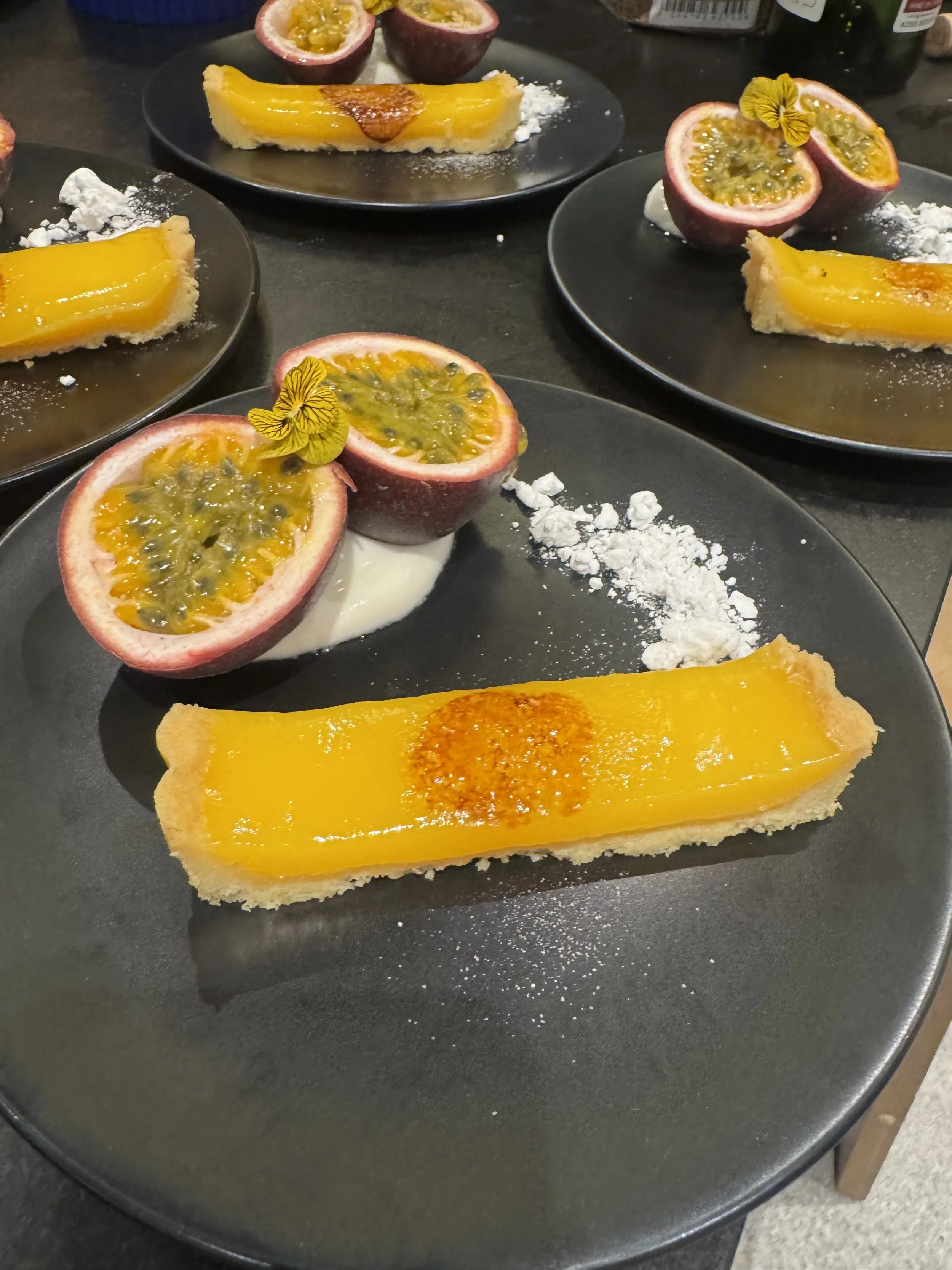 Dessert plates with passion fruit halves, mango tarts, and powdered sugar