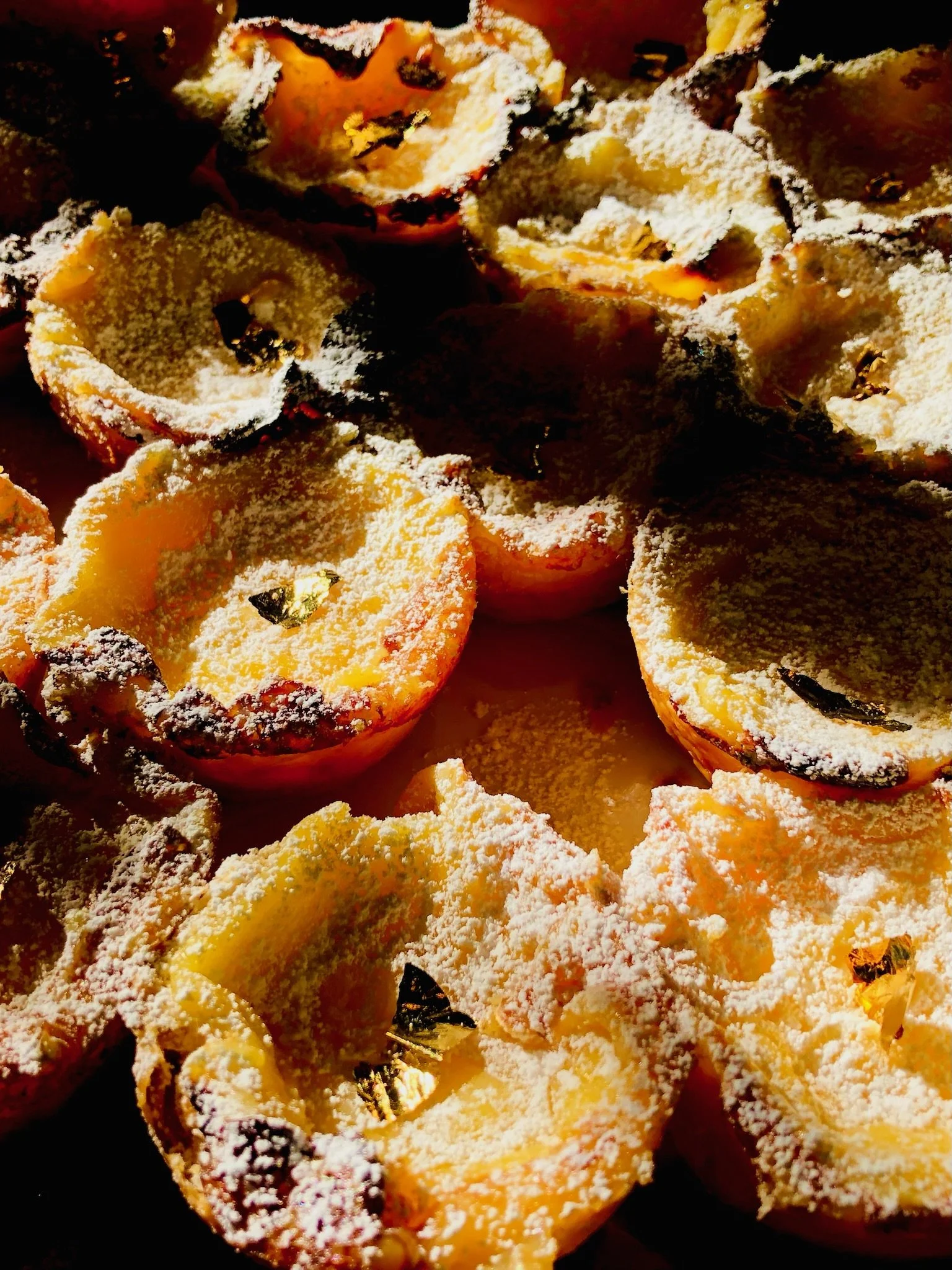 Close-up of Portuguese tarts sprinkled with powdered sugar.